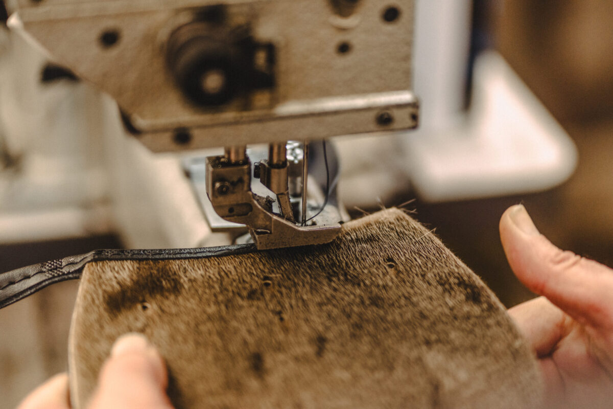 Hands stitching a hide-front sporran piece in the Glasgow workshop