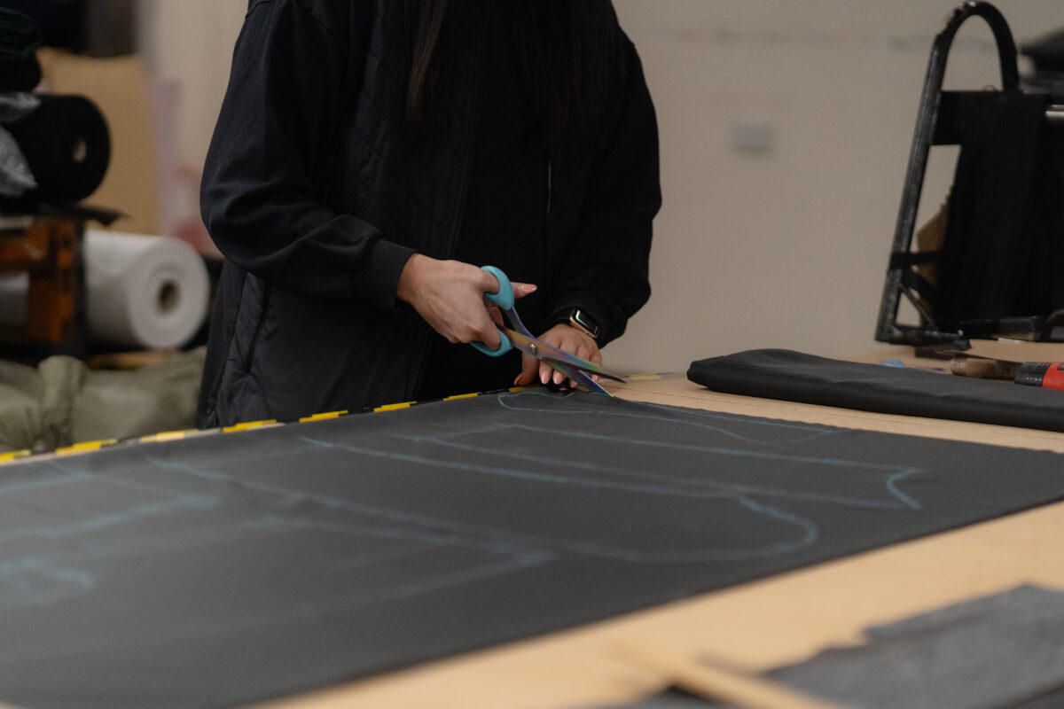 Hands cutting marked tailoring cloth with shears in the Glasgow workshop