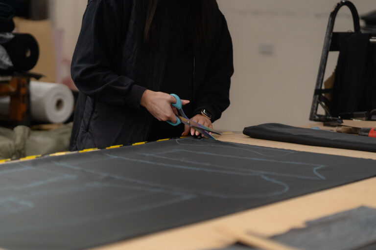 Hands cutting marked tailoring cloth with shears in the Glasgow workshop