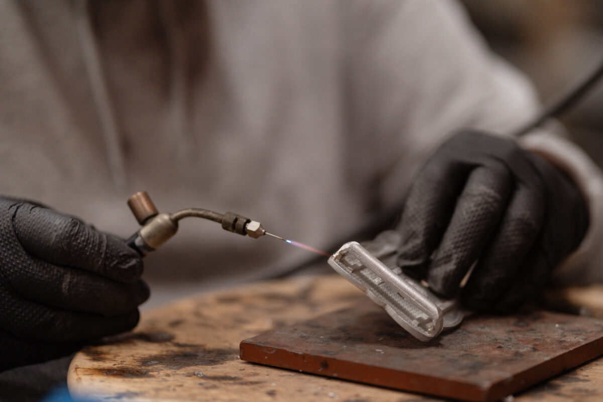 Gloved hands working on a metal component in the Glasgow workshop